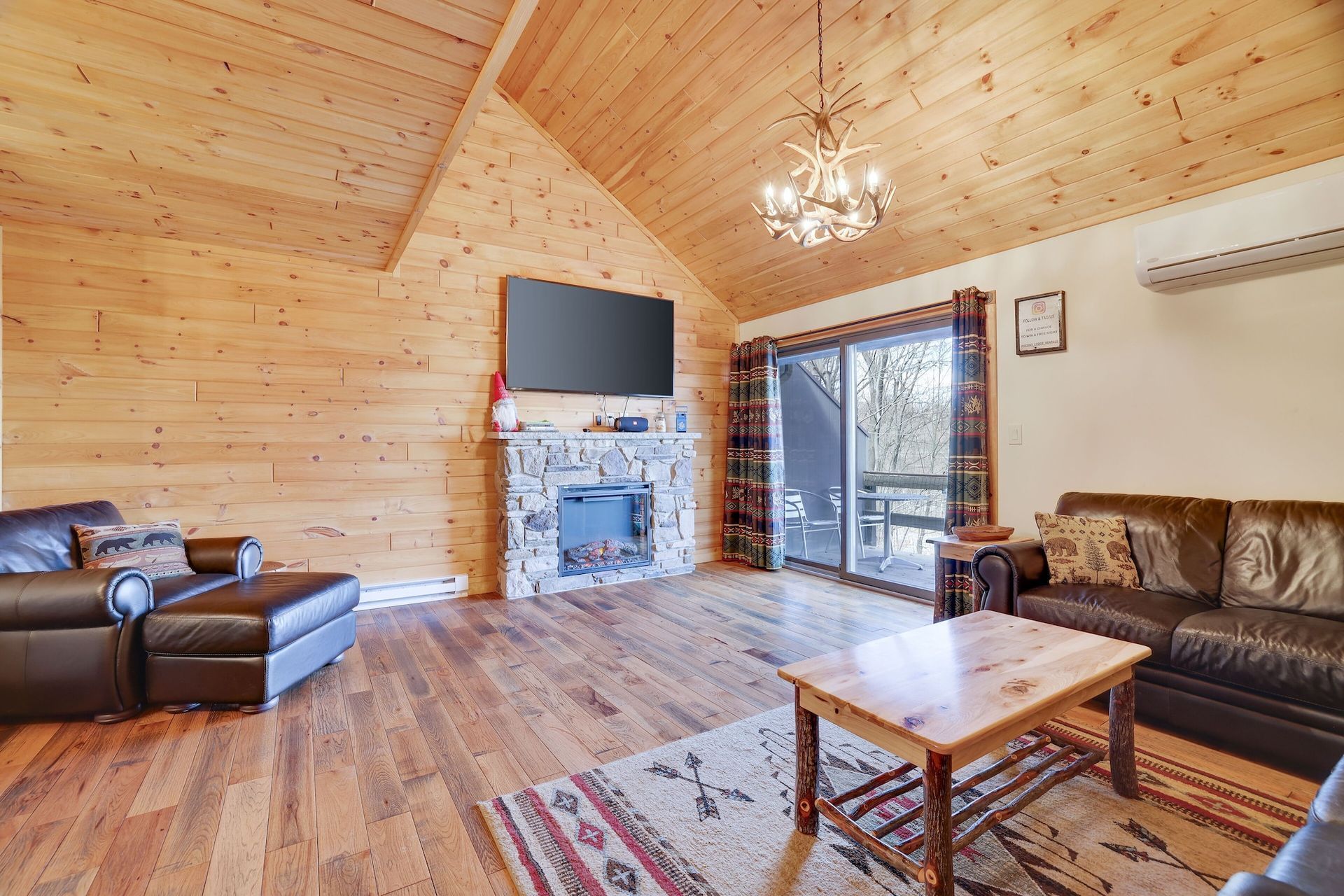 A living room with a couch , chairs , coffee table and television.