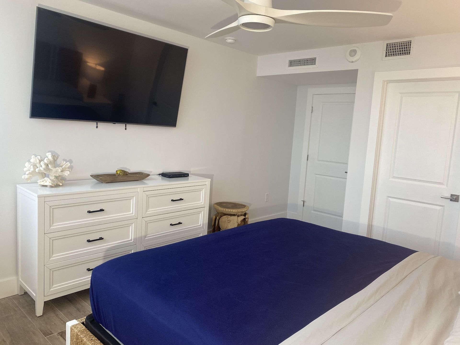 A bedroom with a bed , dresser , television and ceiling fan