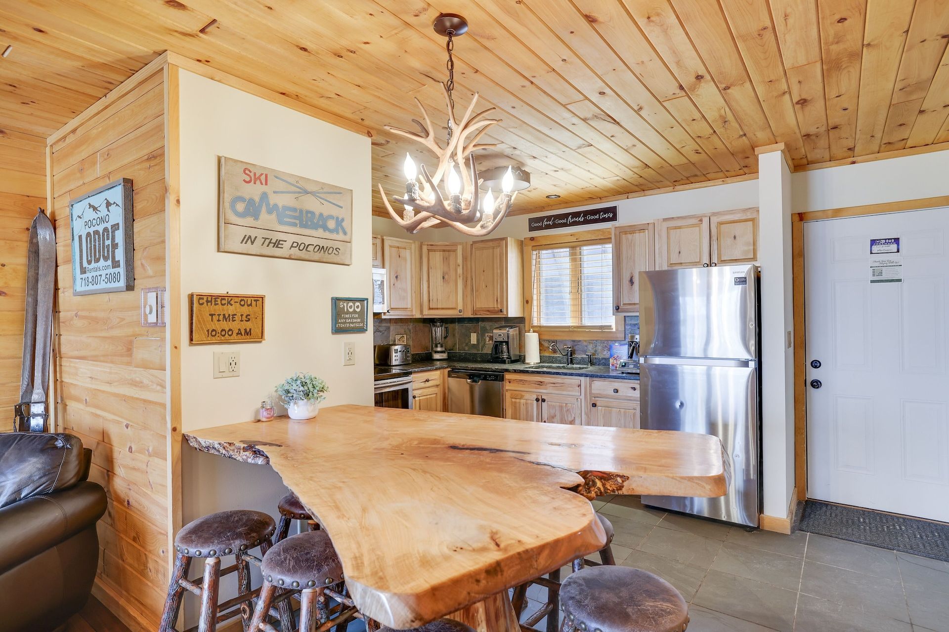 A kitchen with a wooden table and stools and a stainless steel refrigerator.