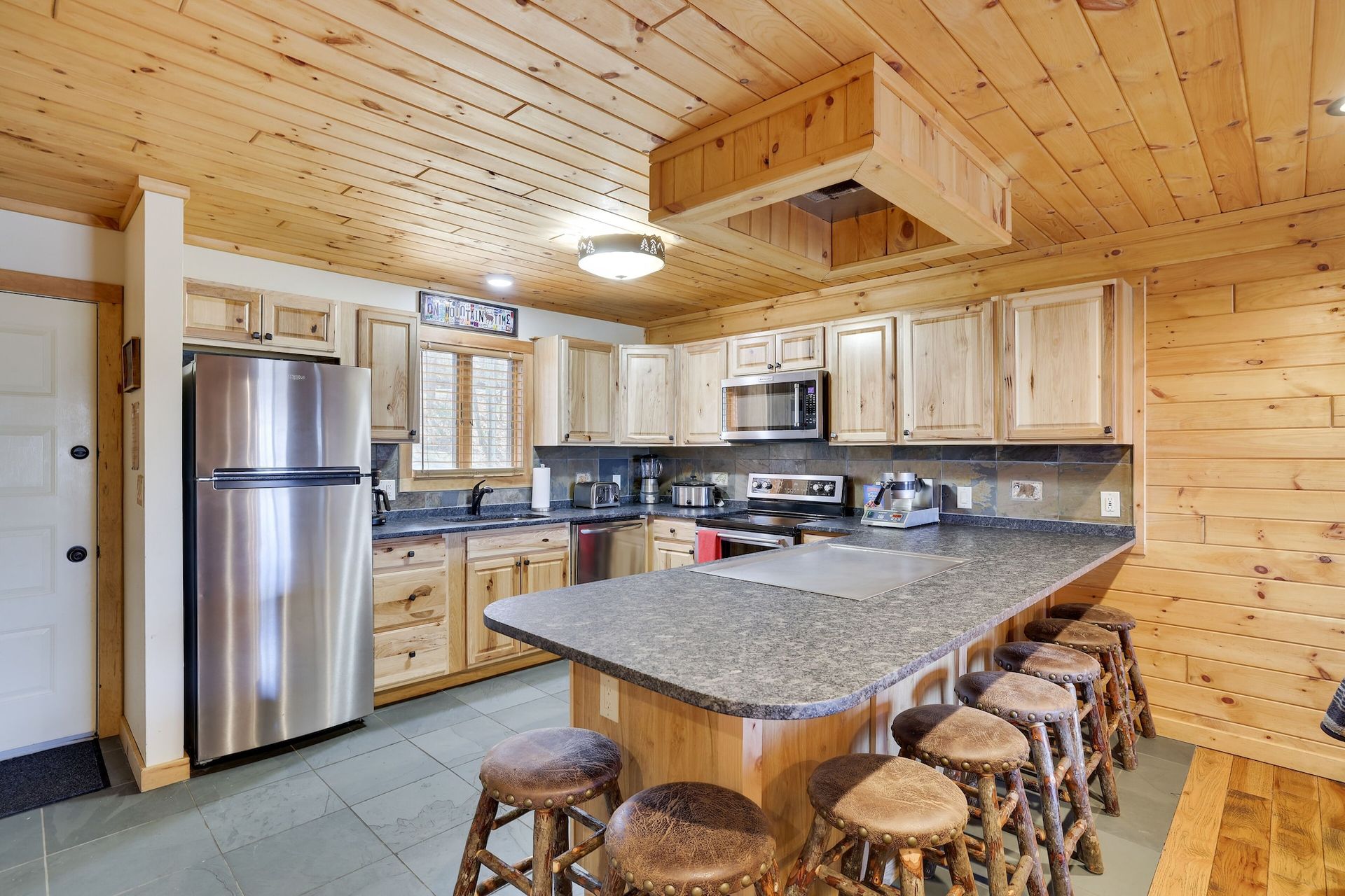A kitchen in a log cabin with stainless steel appliances and granite counter tops.