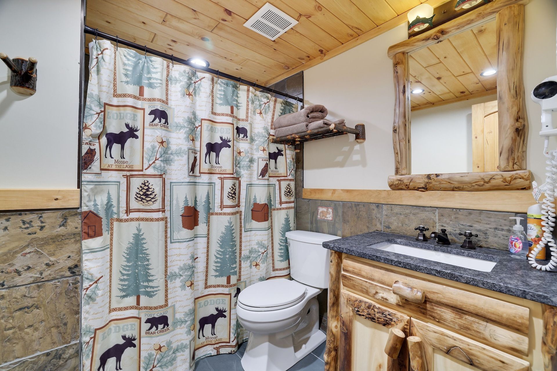 A bathroom with a toilet , sink , mirror and shower curtain.