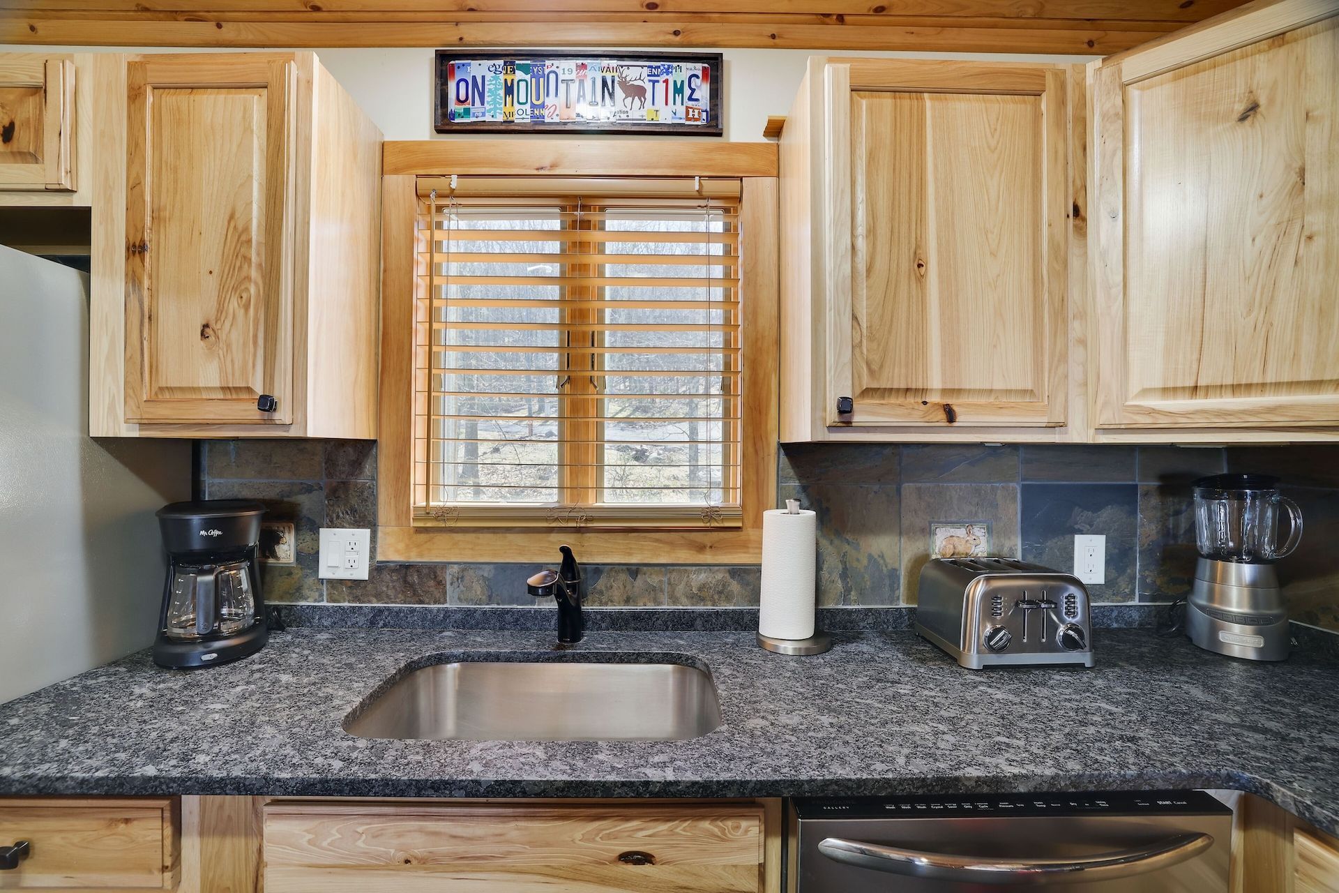 A kitchen with granite counter tops , stainless steel appliances , and wooden cabinets.