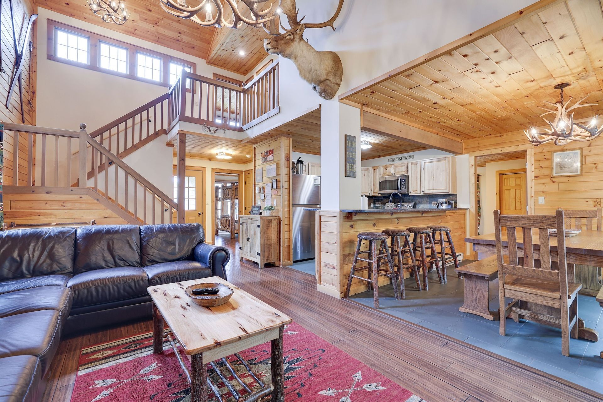 A living room in a log cabin with a couch , table , chairs and stairs.