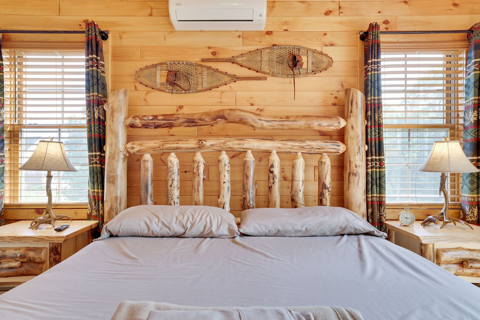 A bedroom in a log cabin with a wooden headboard and snowshoes on the wall.