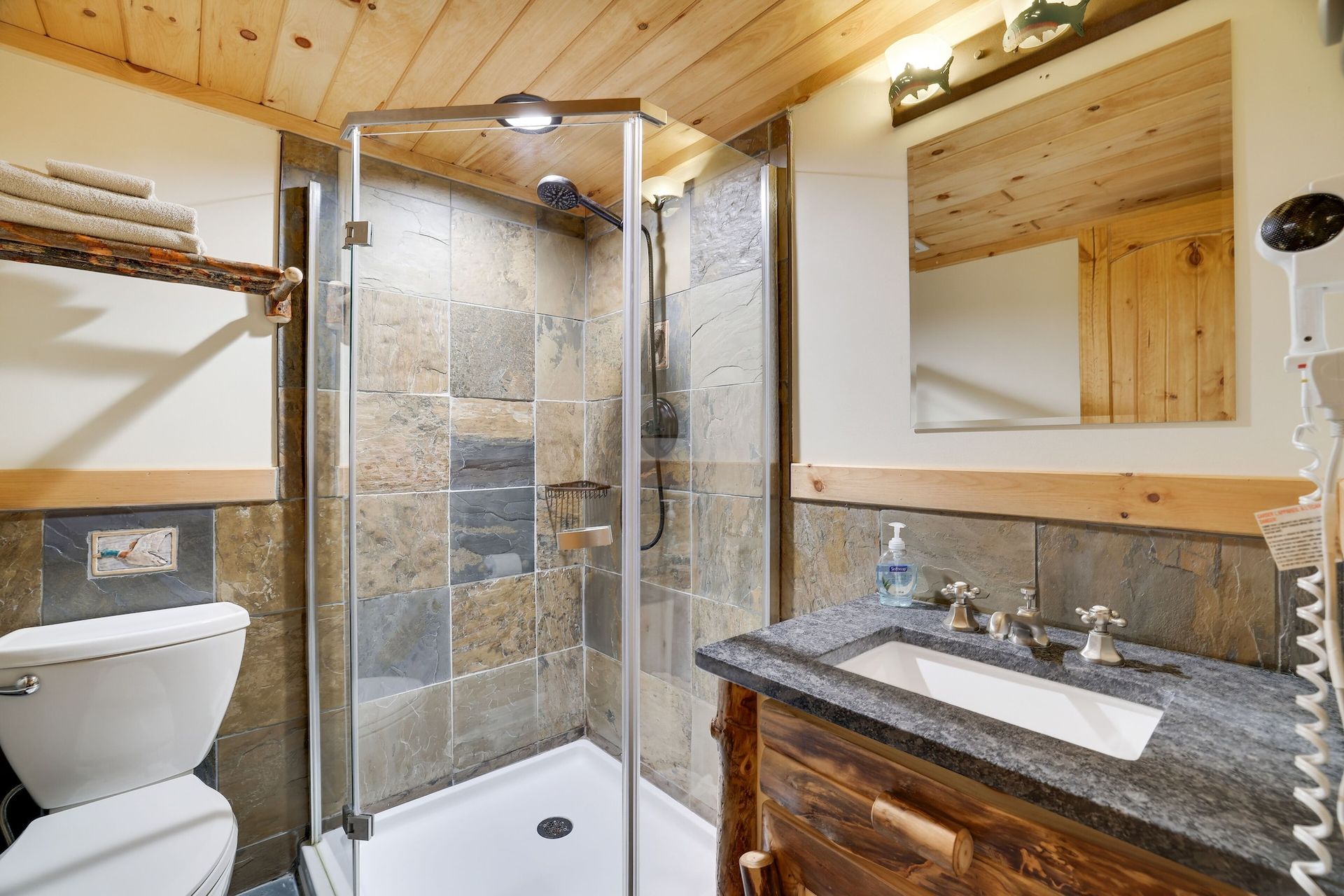 A bathroom with a toilet , sink and shower.