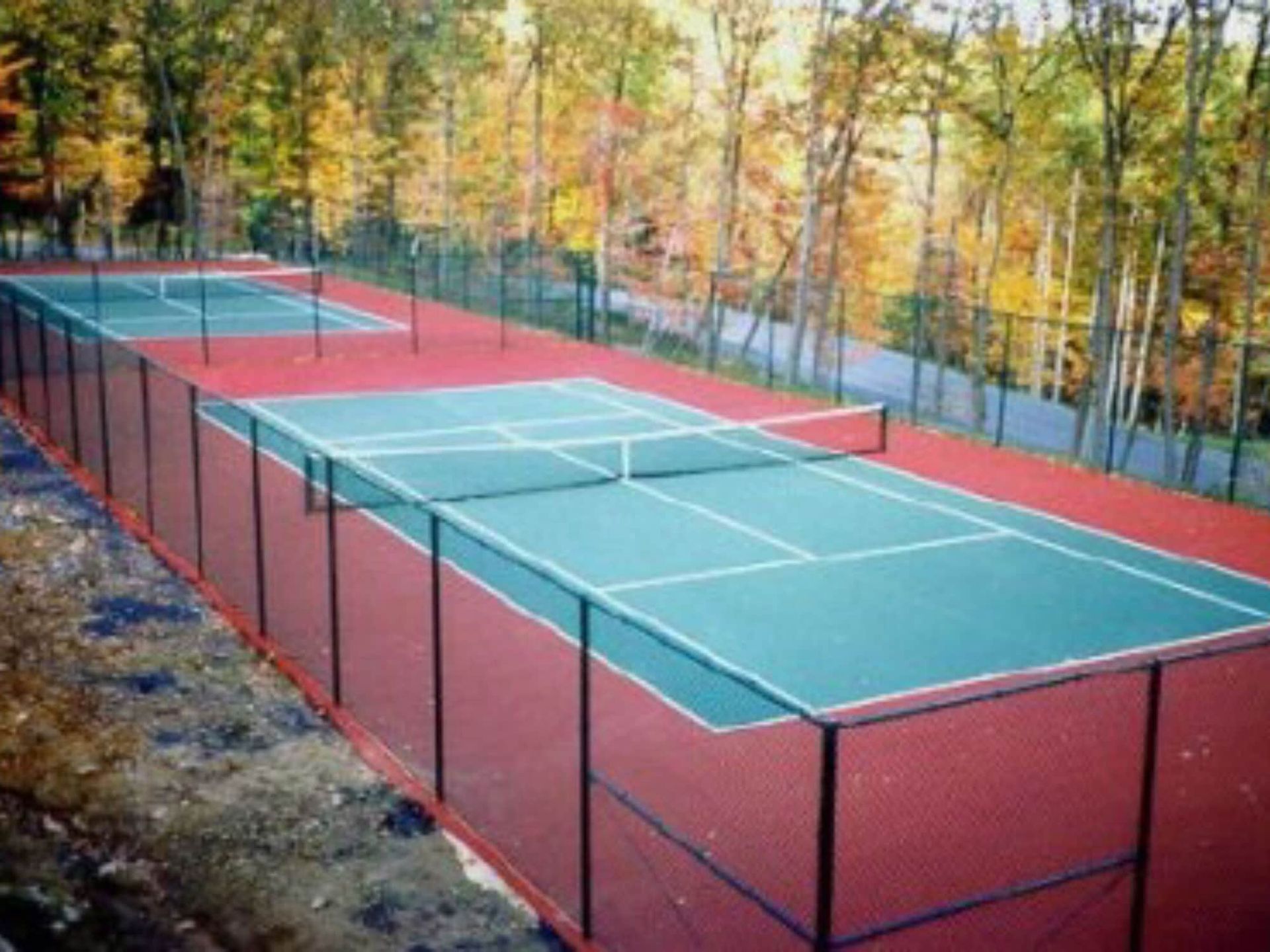 A tennis court with a fence around it and trees in the background