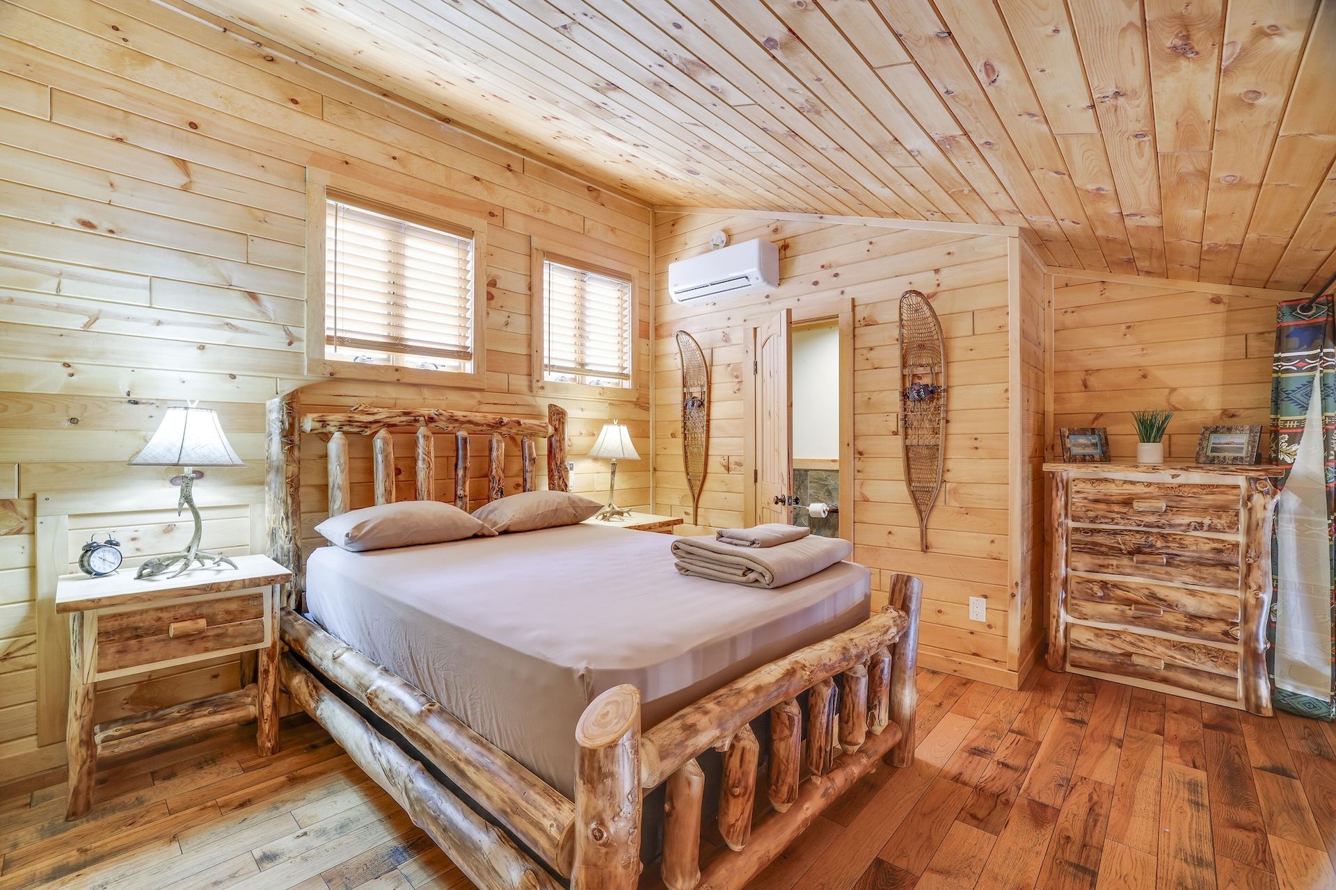 A bedroom in a log cabin with a king size bed and a dresser.