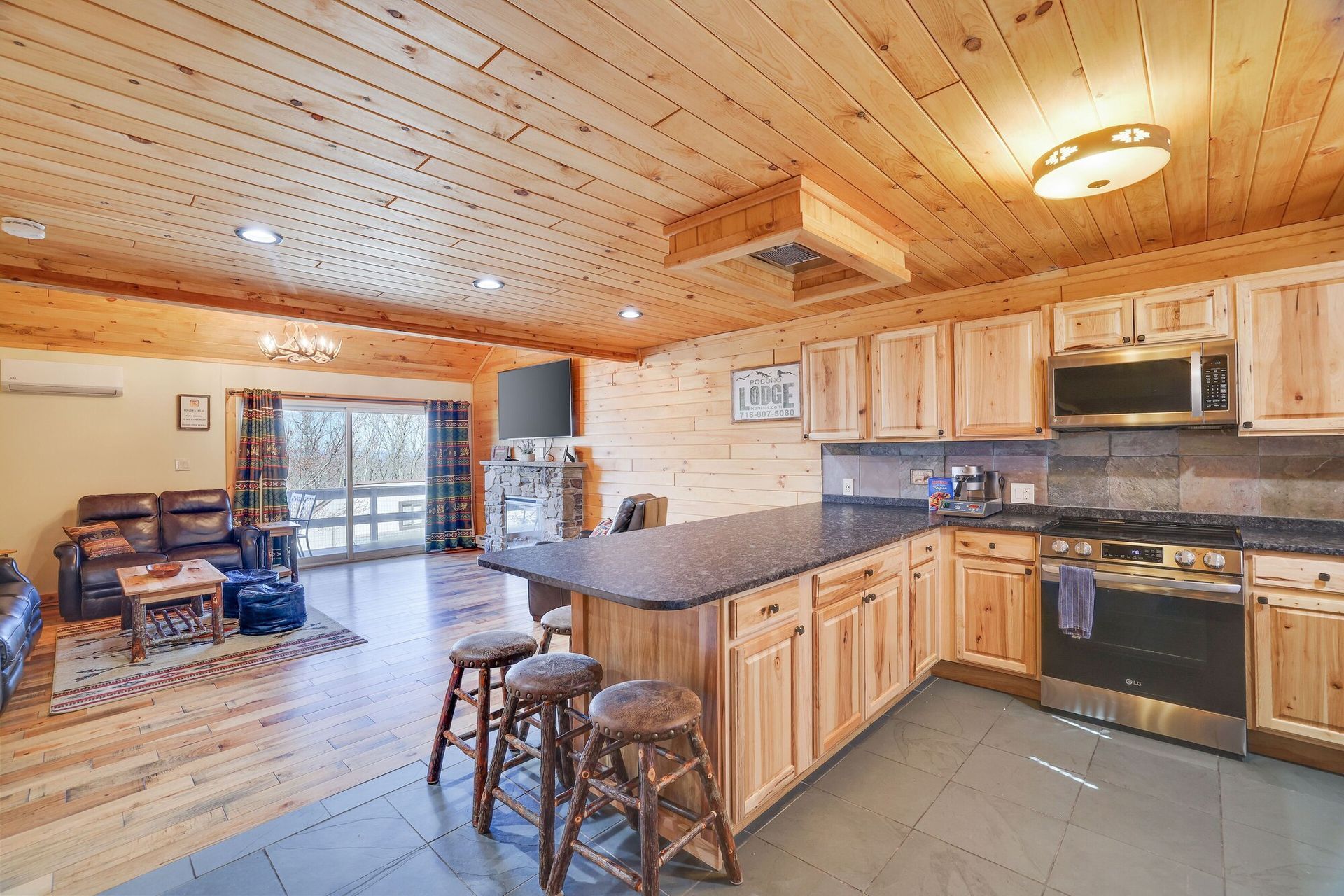 A kitchen in a log cabin with wooden cabinets and stools.
