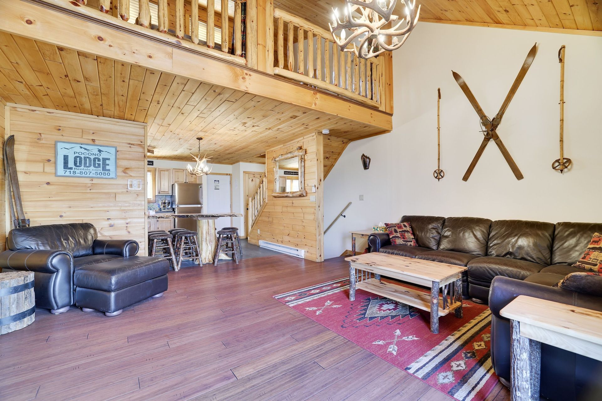 A living room with a couch , chair , coffee table and skis on the wall.