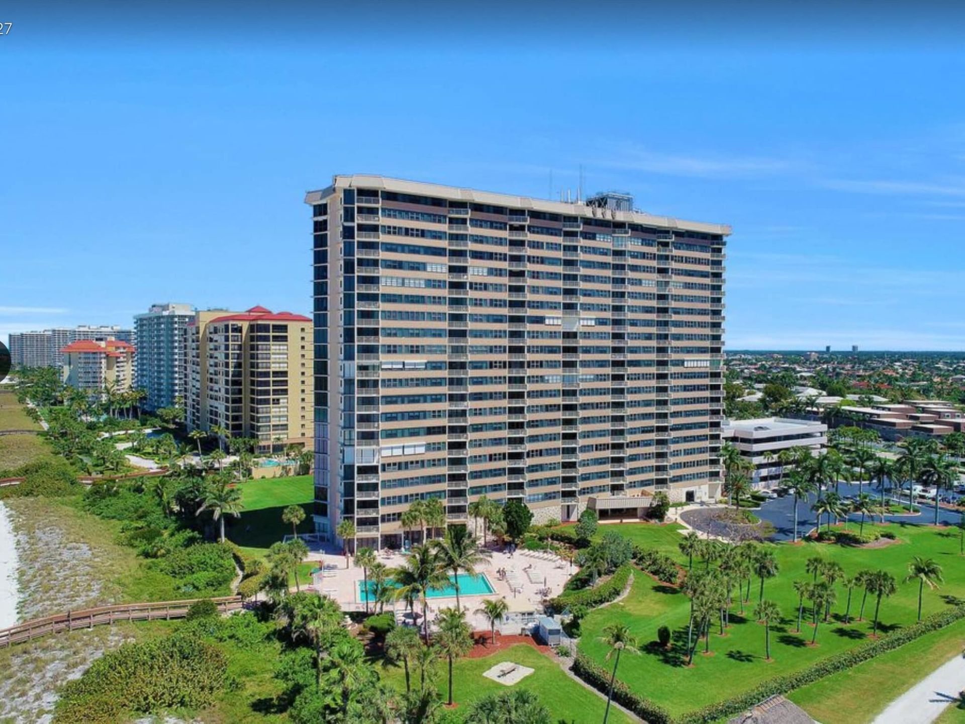 An aerial view of a large building surrounded by palm trees.