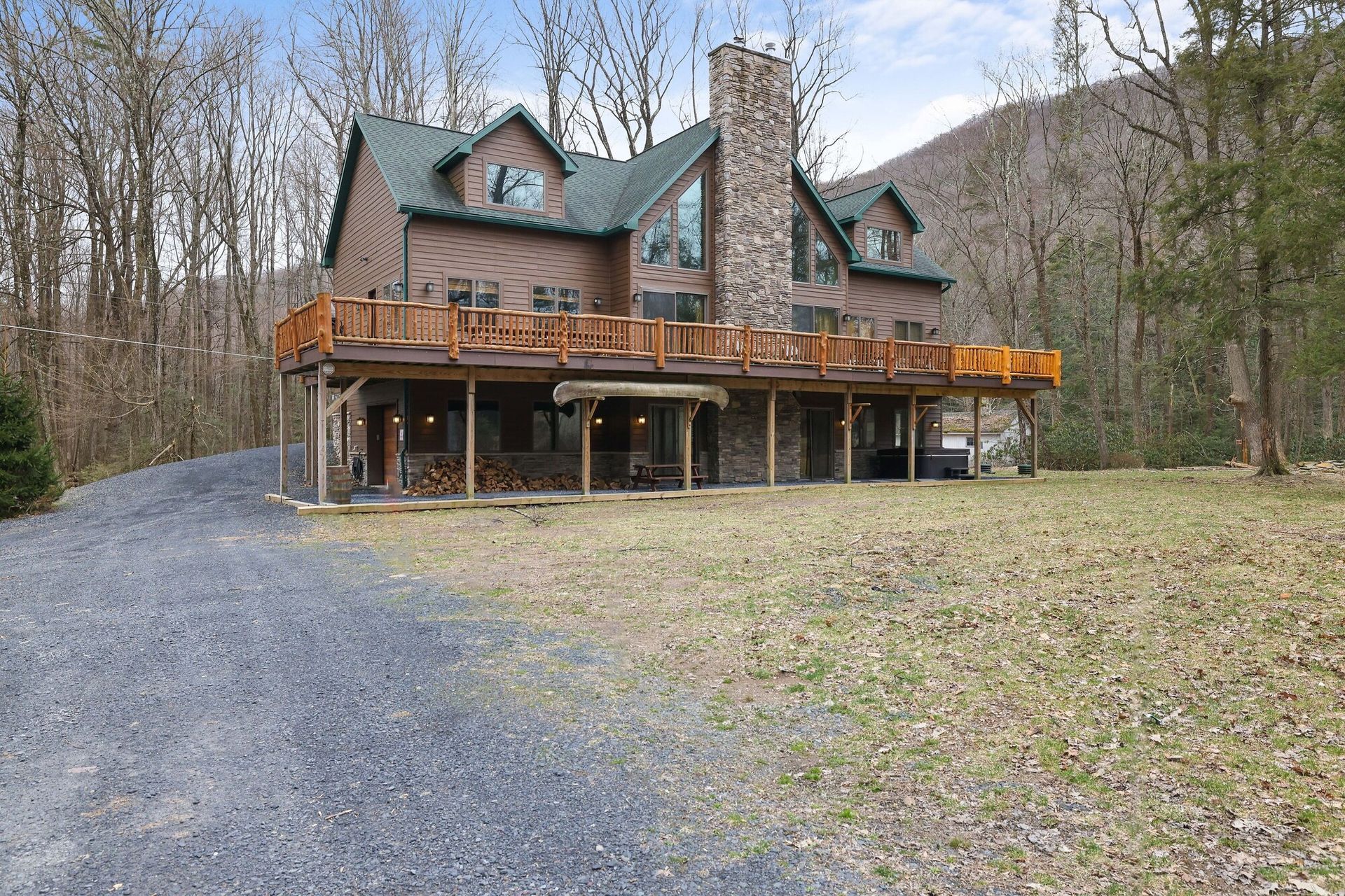 A large house with a large deck in the middle of a forest.