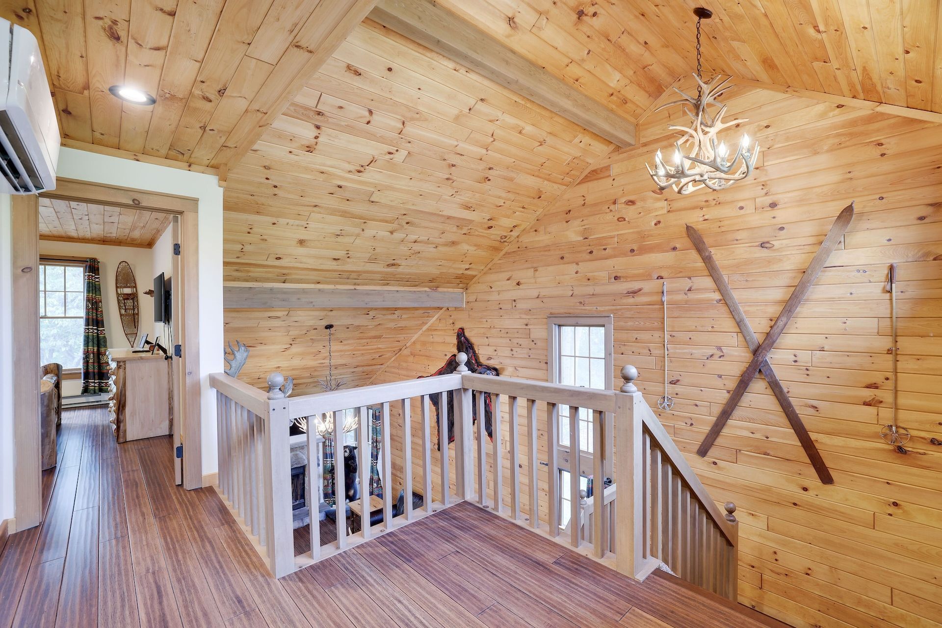 A wooden staircase in a log cabin with skis on the wall.