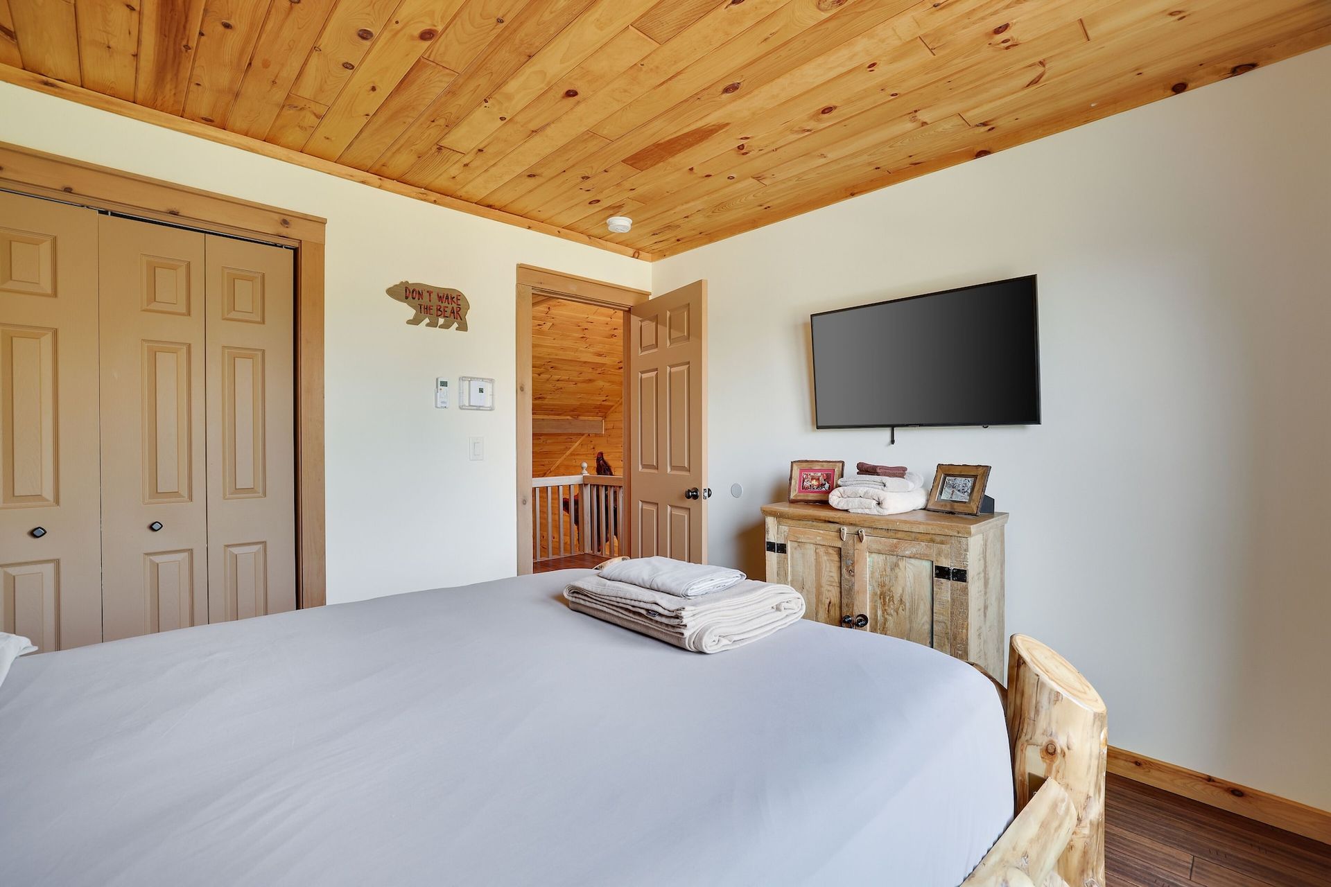 A bedroom with a king size bed and a flat screen tv on the wall.
