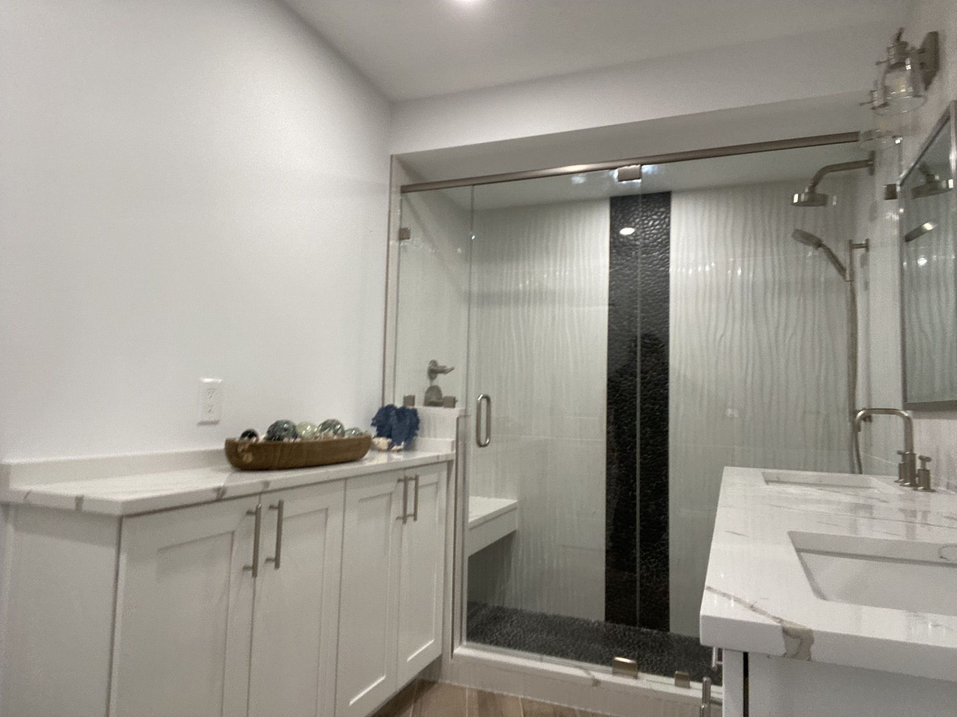 A bathroom with a walk in shower , sink and mirror.