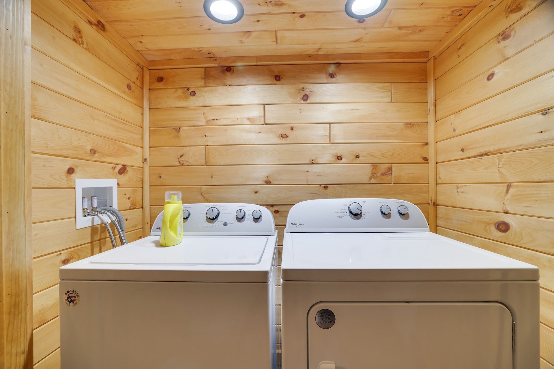 A laundry room with a washer and dryer in a log cabin.