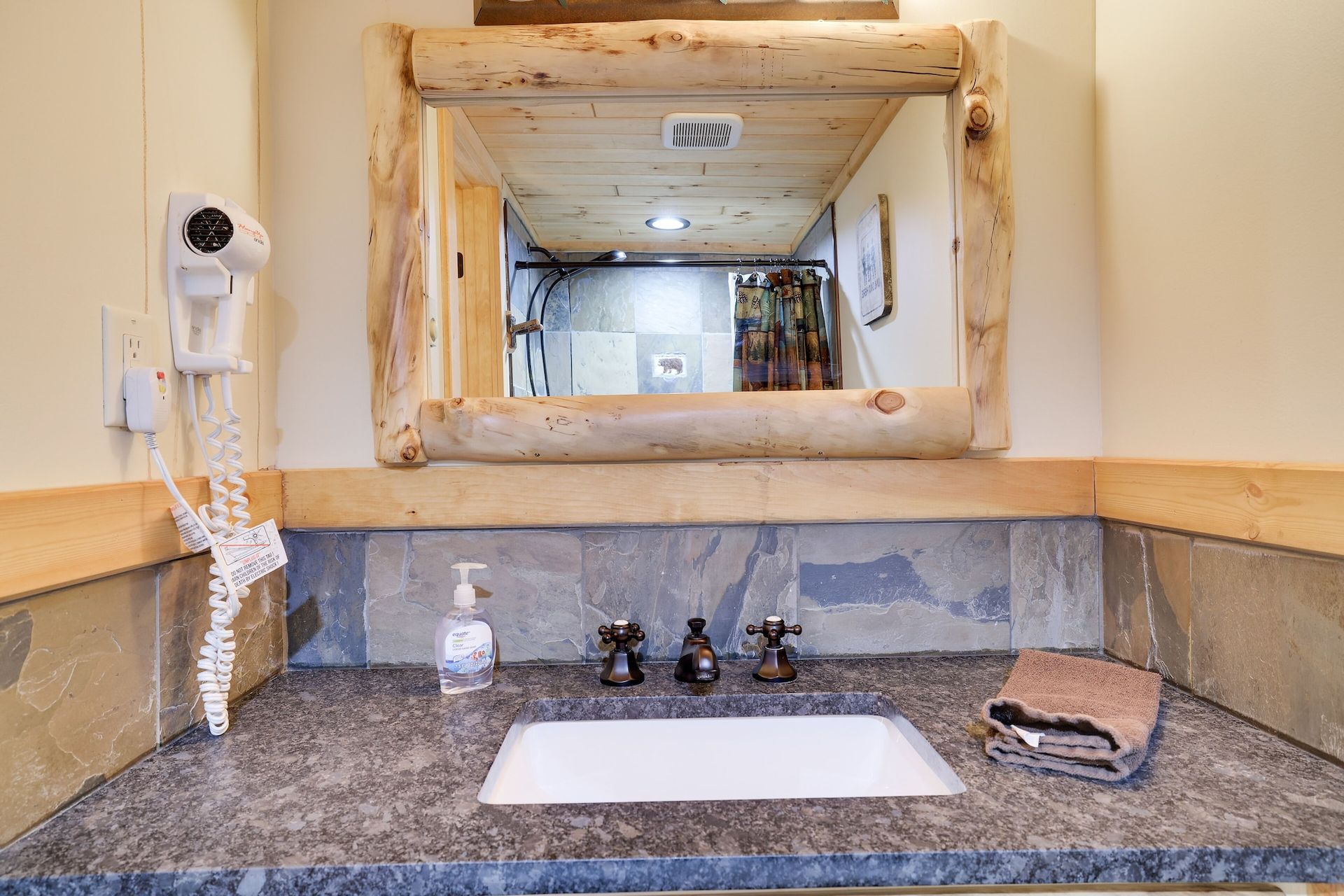 A bathroom with a sink , mirror and hair dryer.
