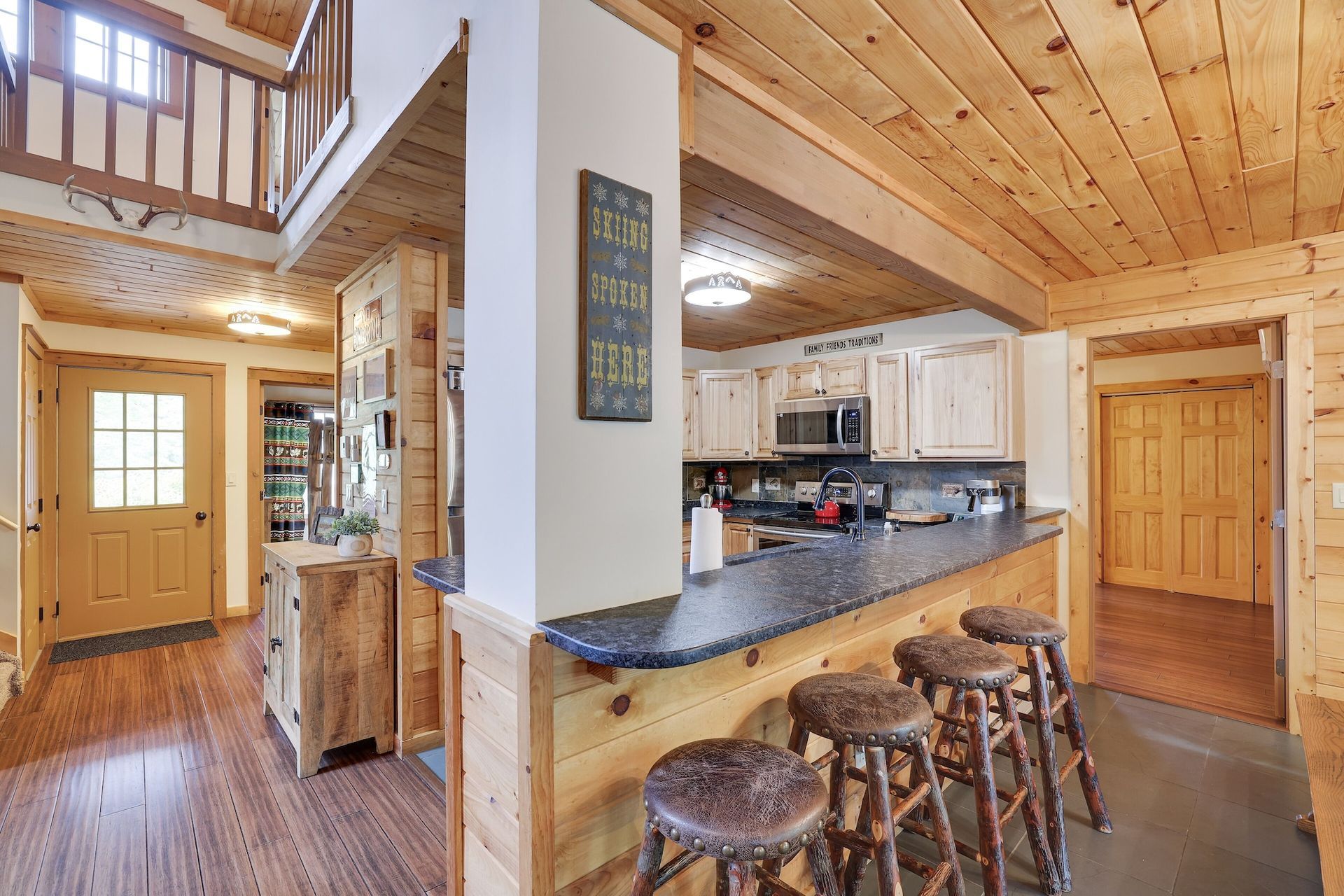 A kitchen in a log cabin with a bar and stools.