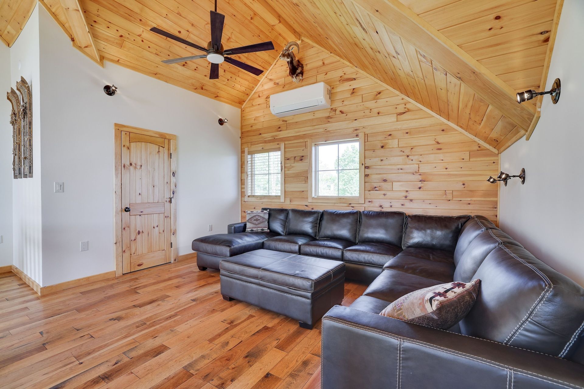 A living room with a large sectional couch and a ceiling fan.