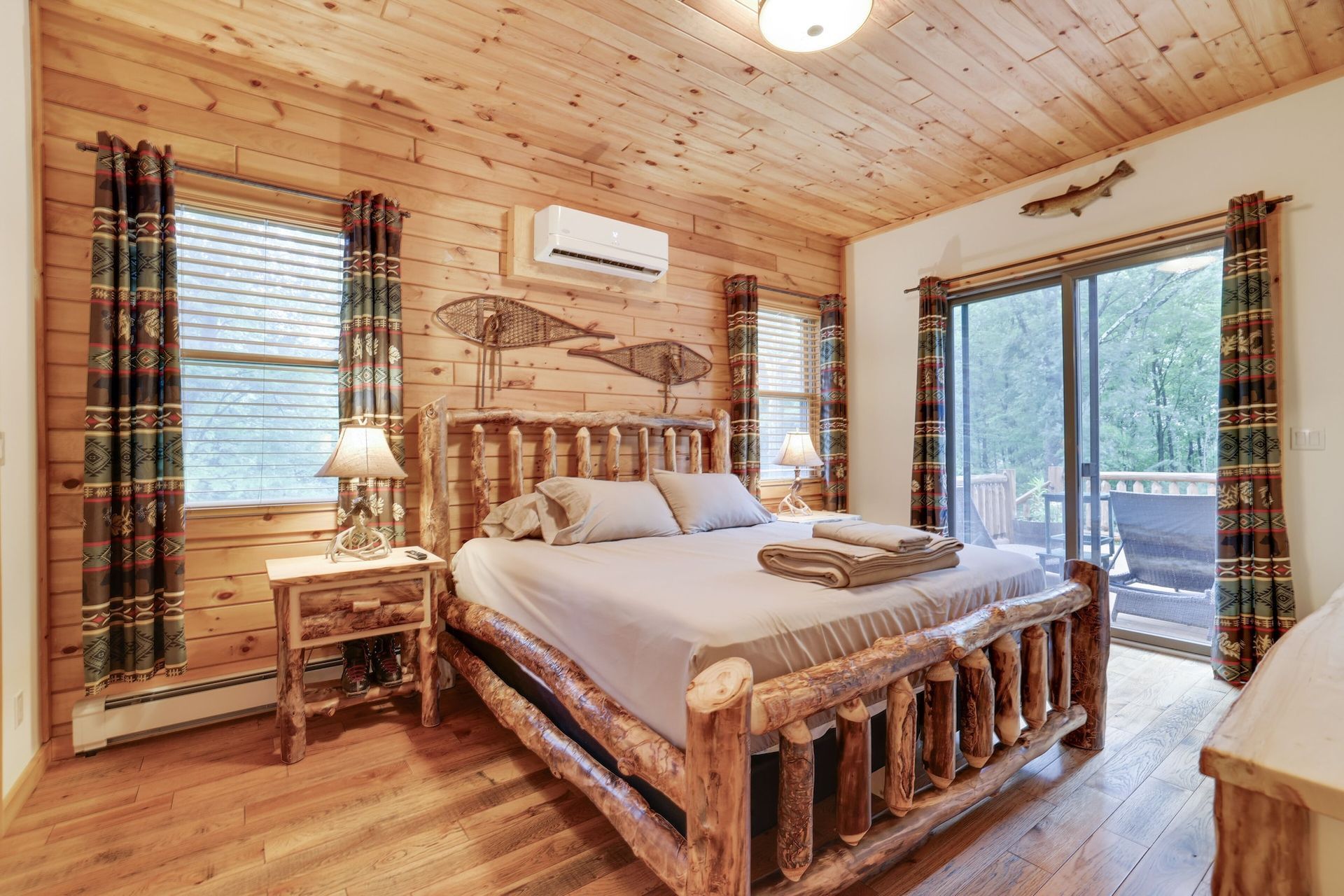 A bedroom in a log cabin with a king size bed and sliding glass doors.