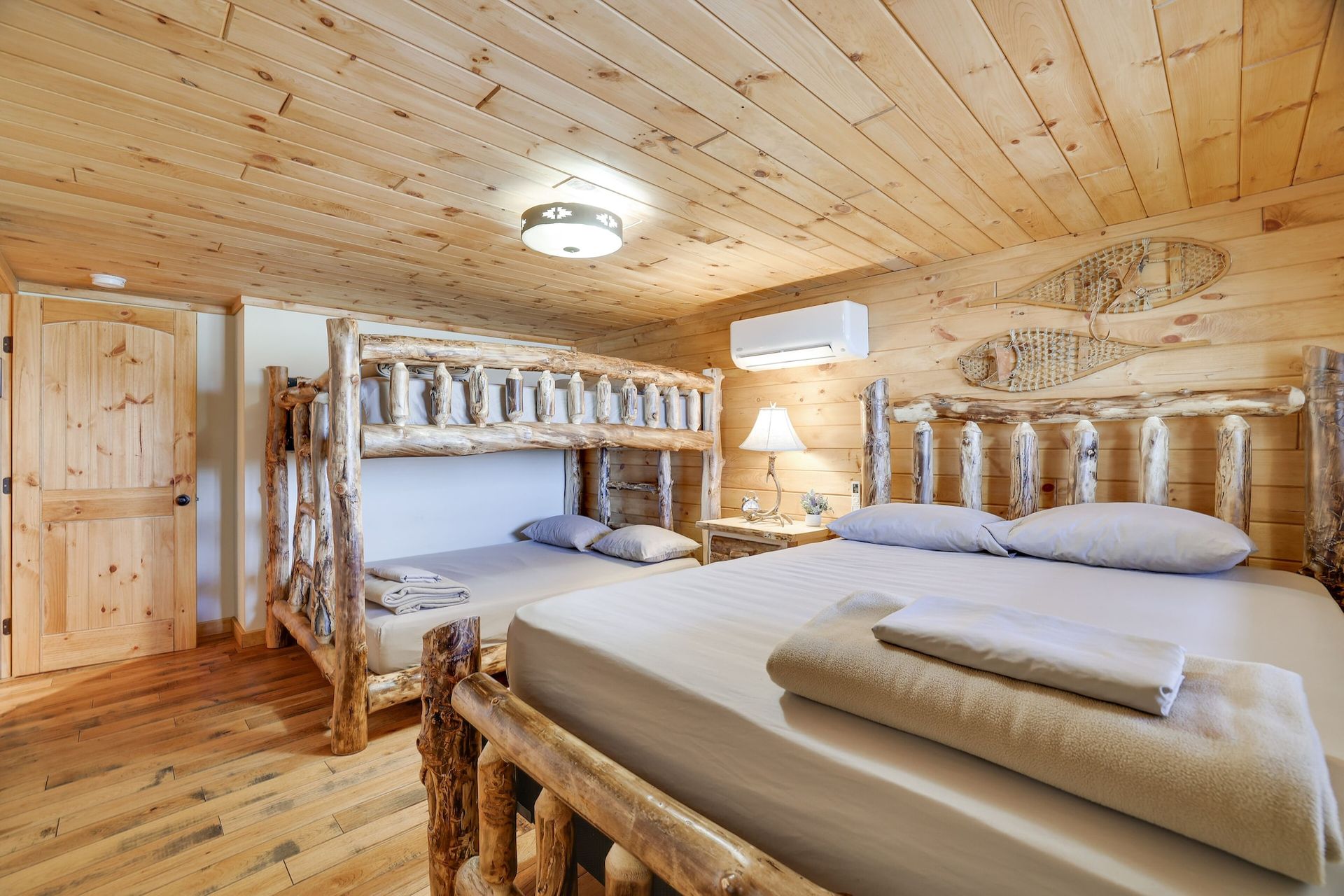 A bedroom in a log cabin with two beds and a bunk bed.