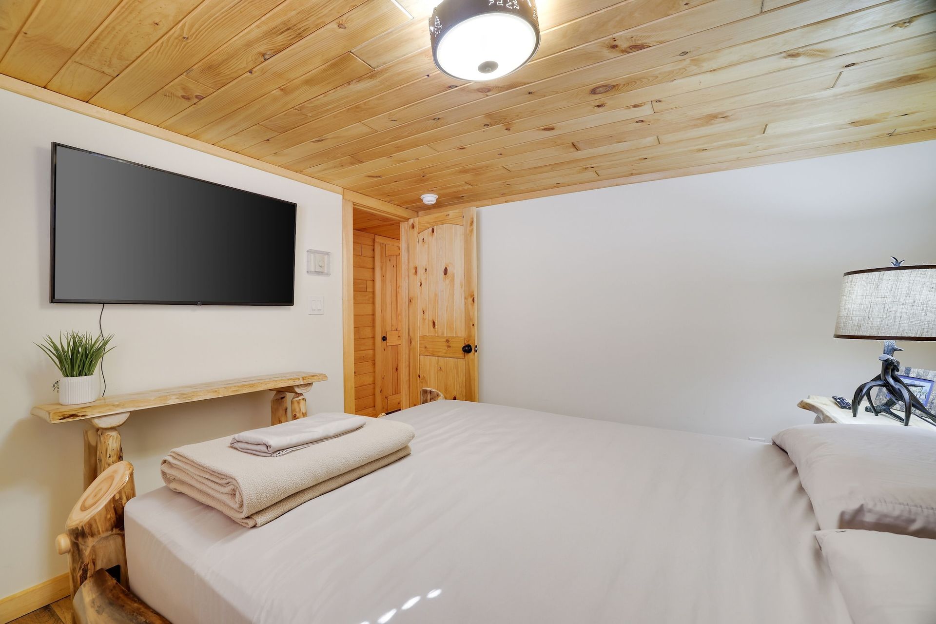 A bedroom with a large bed and a flat screen tv on the wall.