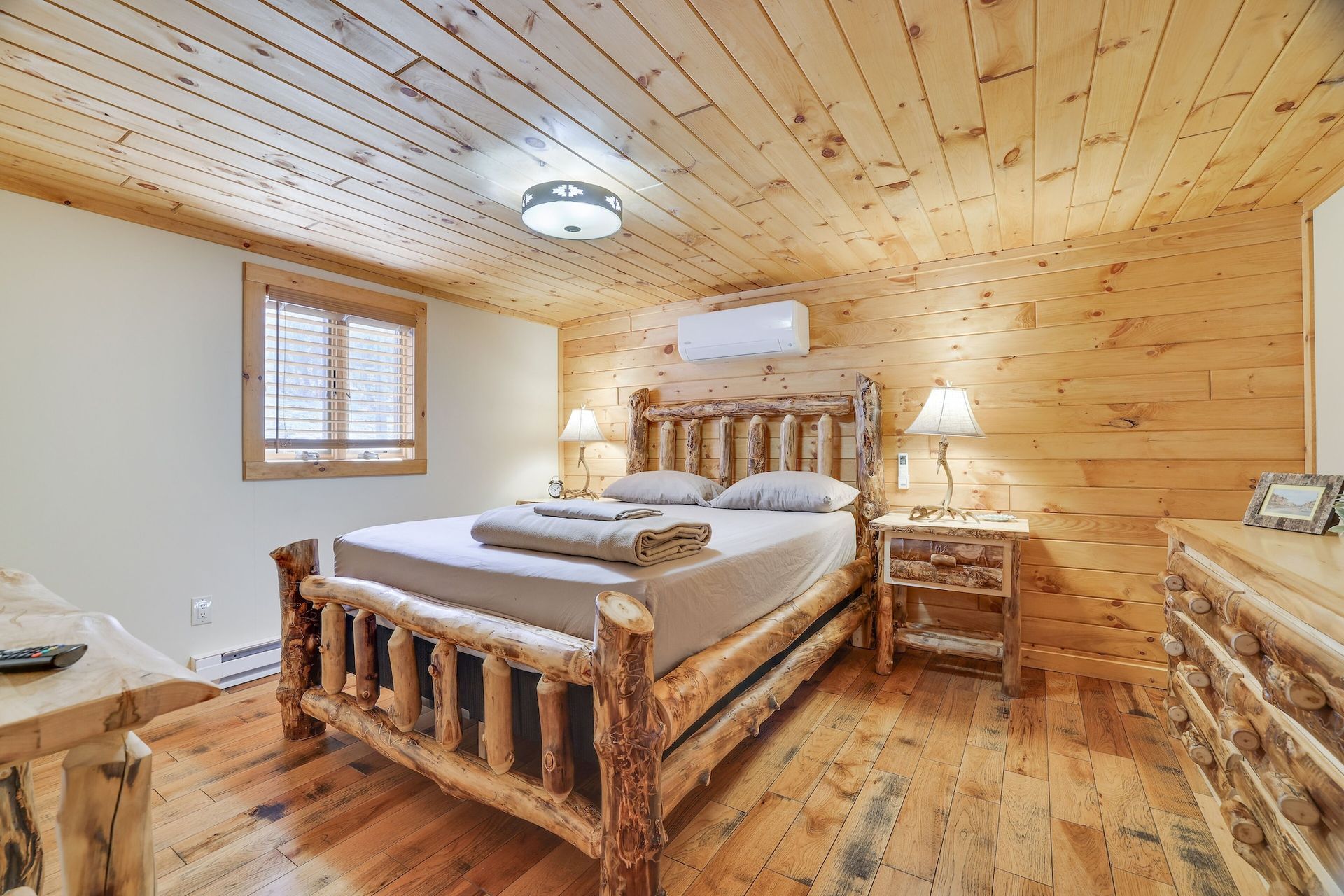 A bedroom in a cabin with a log bed and wooden floors.