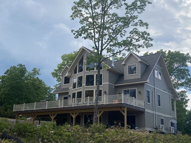 A large house with a large deck and a tree in front of it