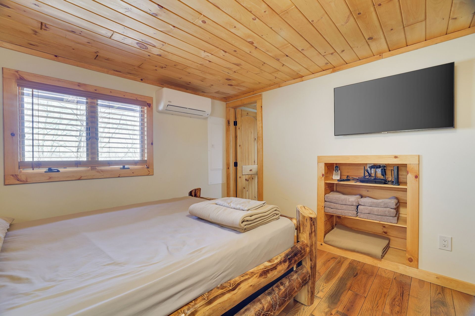A bedroom with a bed and a flat screen tv on the wall.