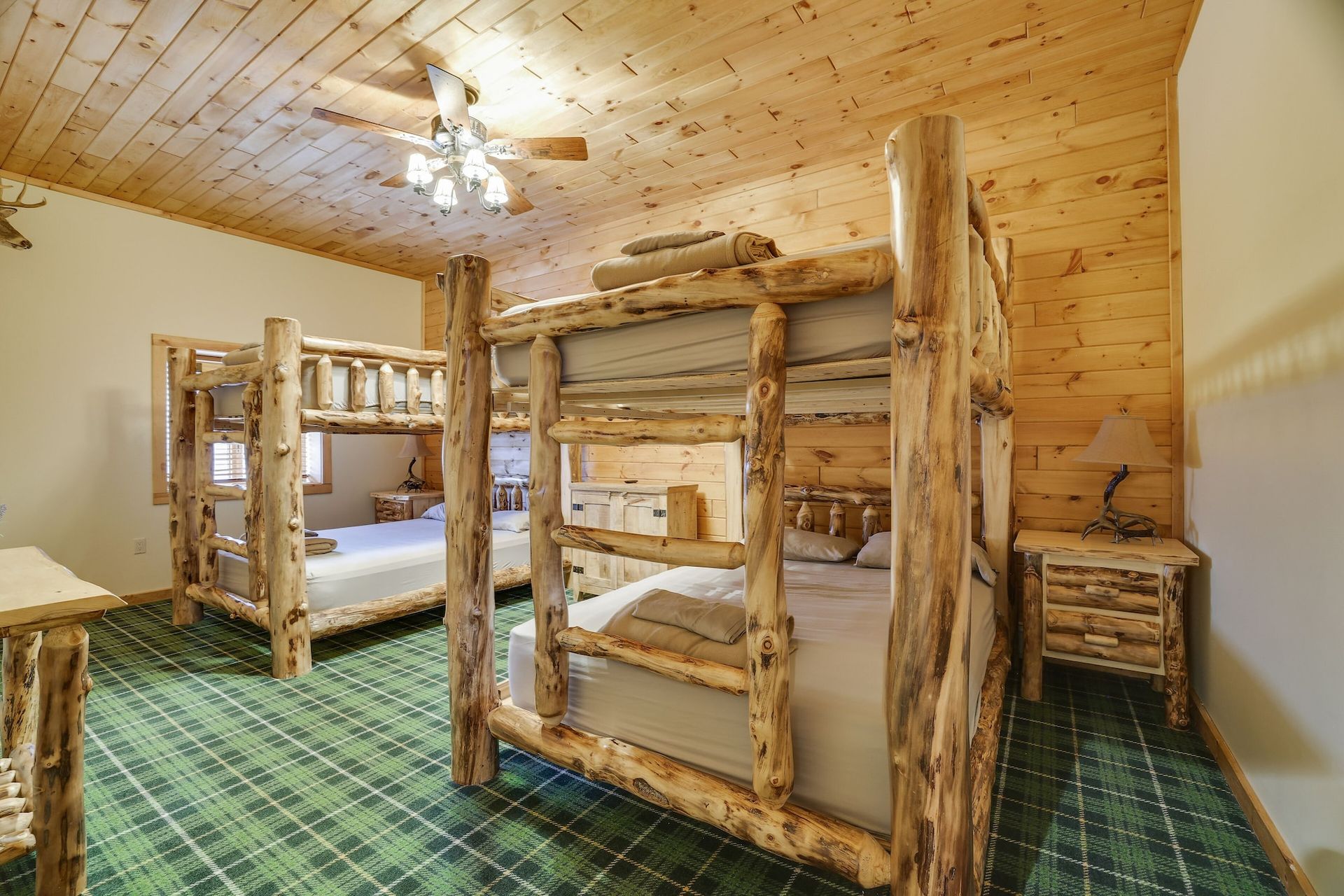 A room with bunk beds made of logs and a ceiling fan.