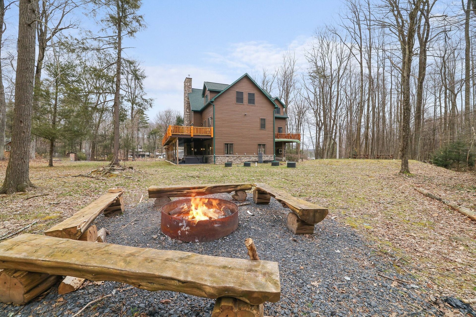 There is a fire pit in the middle of the woods in front of a log cabin.