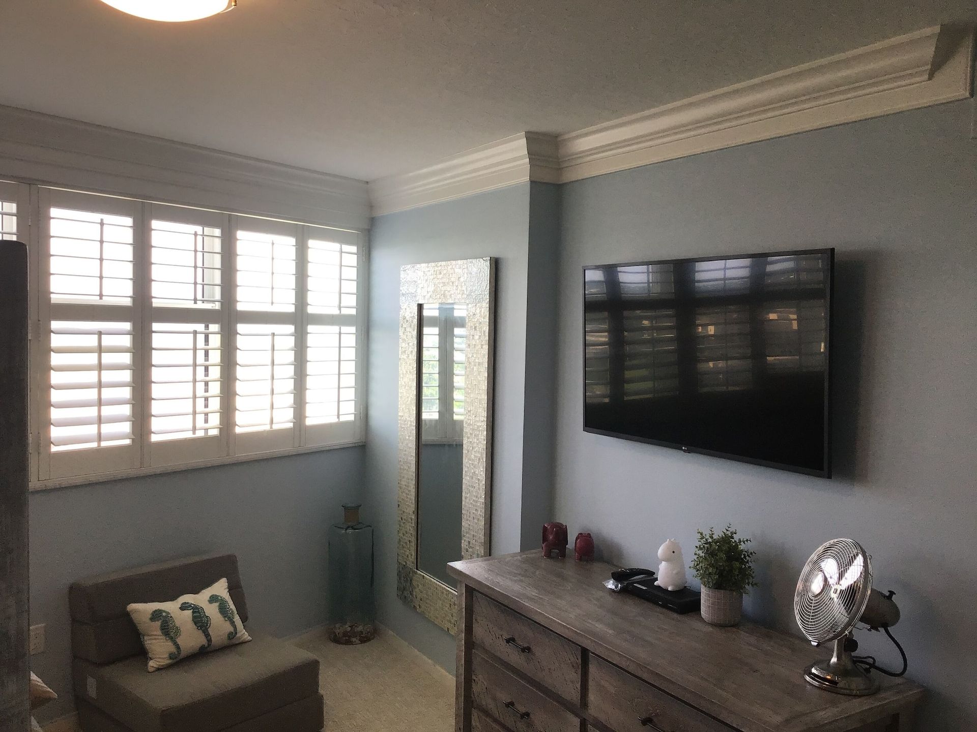 A living room with a dresser and a flat screen tv on the wall.