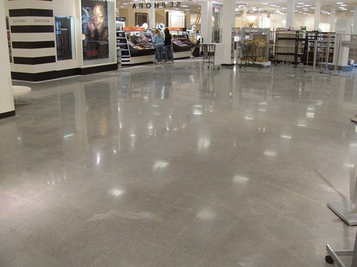 Empty shopping mall corridor with shiny gray floor and storefronts in the background