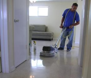 Worker buffing a shiny floor in a hallway with a floor polisher.