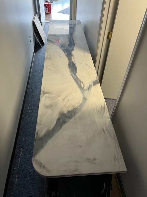 Long, metallic-looking countertop with swirling gray and white patterns in a narrow hallway.