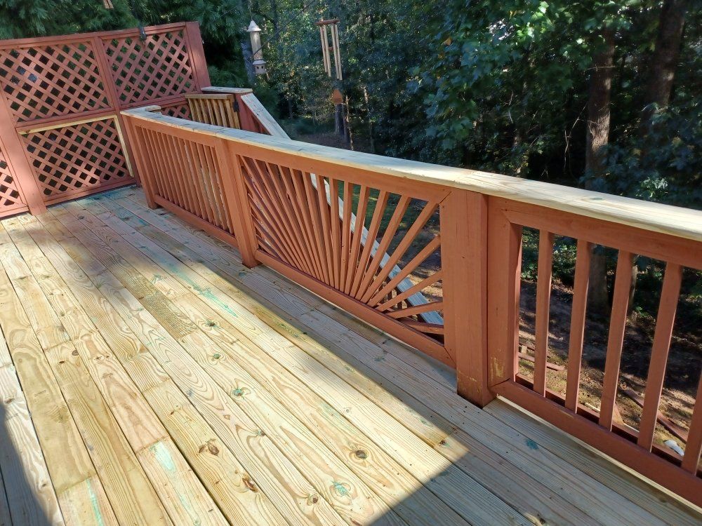 Wooden deck with ornate orange railing and lattice, surrounded by trees.