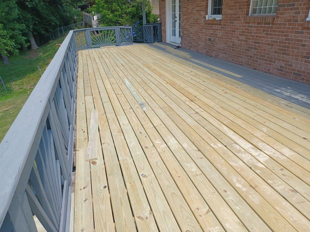 Wooden deck with gray railing, attached to a brick building.