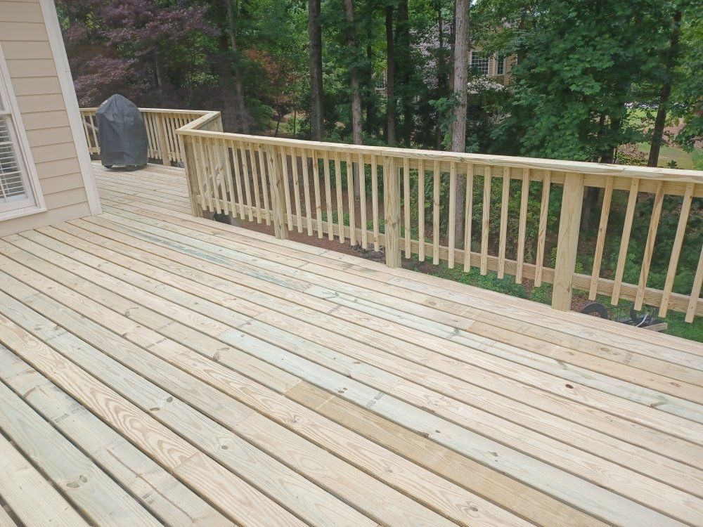 Wooden deck with railing overlooking a wooded area.