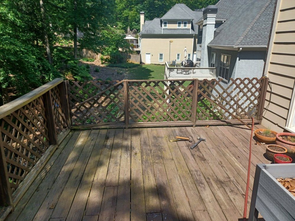 Wooden deck with lattice railing, overlooking a backyard with houses in the background.