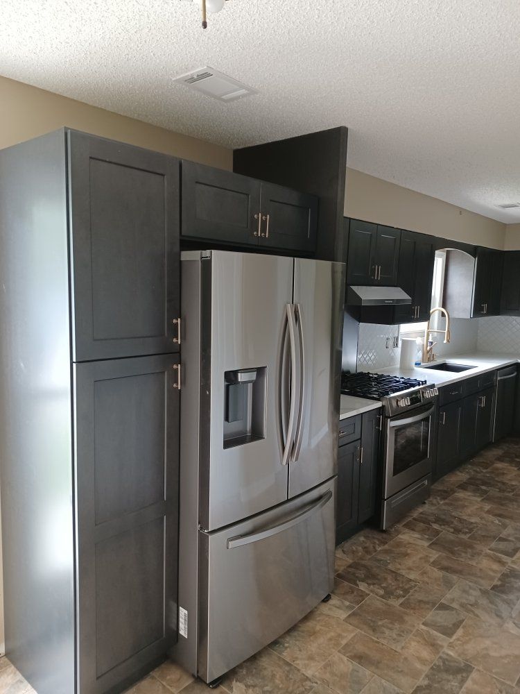 Dark gray kitchen with stainless steel refrigerator and cabinets.