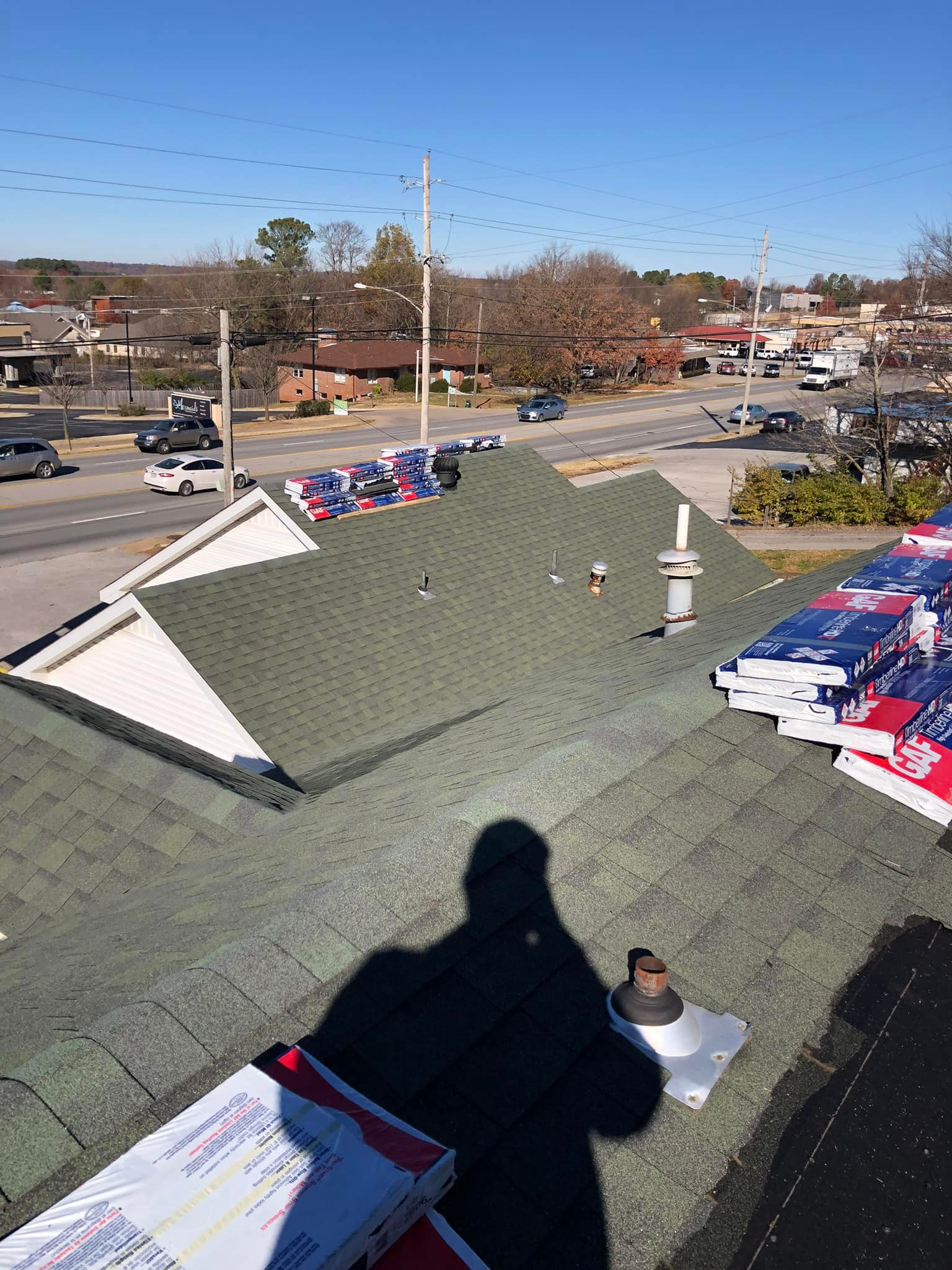 View from a roof over a parking lot, with green shingles, holiday decorations, and a clear blue sky.