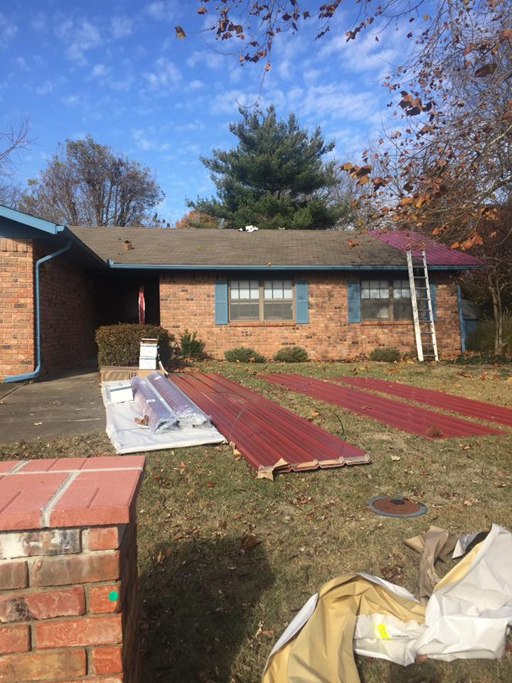 Brick house with roof panels and construction materials in the front yard