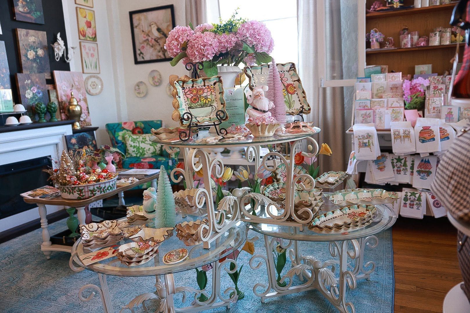 Elegant tea party display with tiered trays, pink flowers, and pastel desserts in a cozy room