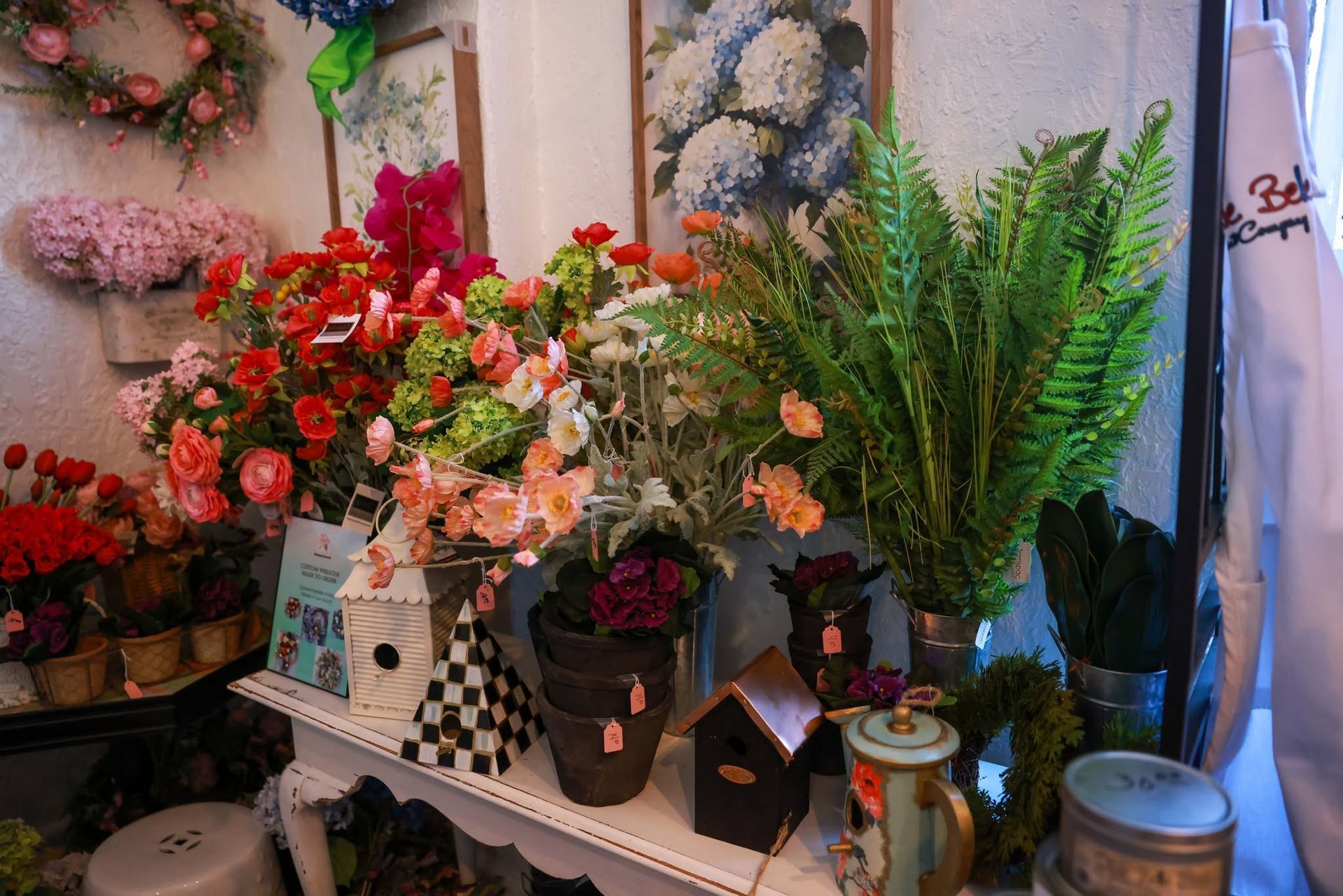 Assorted colorful flower arrangements and green potted plants displayed on a shop shelf