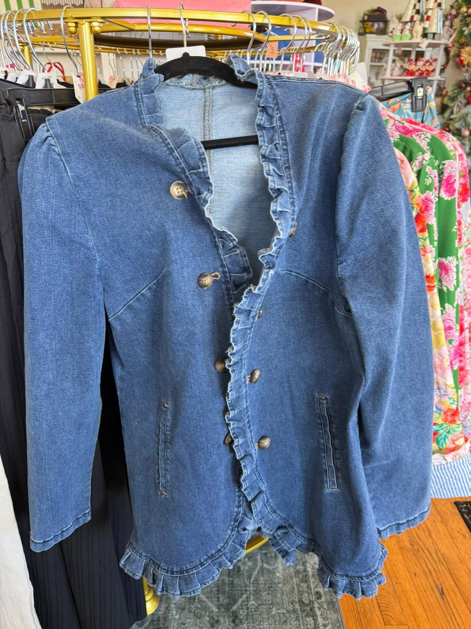 Blue ruffled cardigan with buttons hanging on a rack in a clothing store