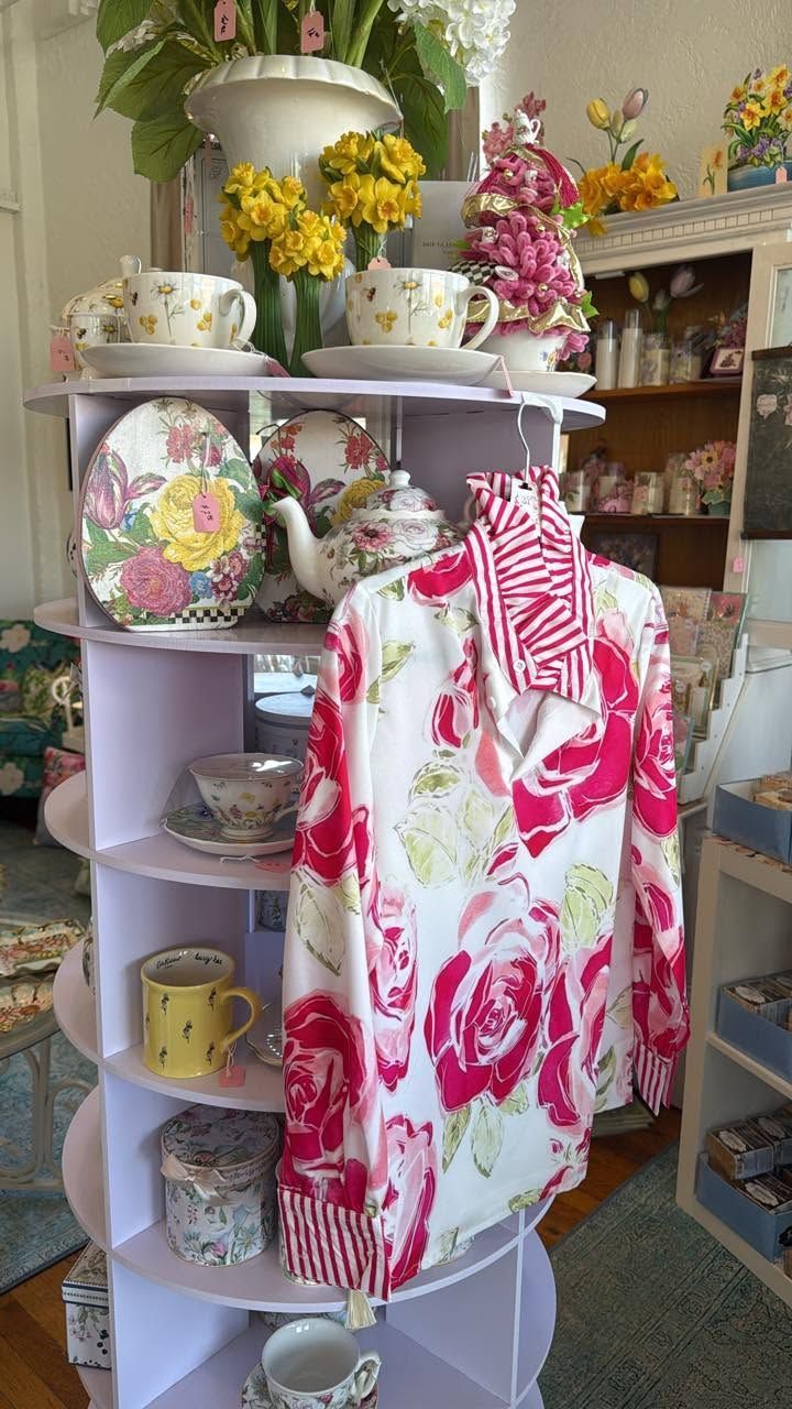 Pink and white floral dress on a mannequin, surrounded by teacups, floral decor, and vintage china display.