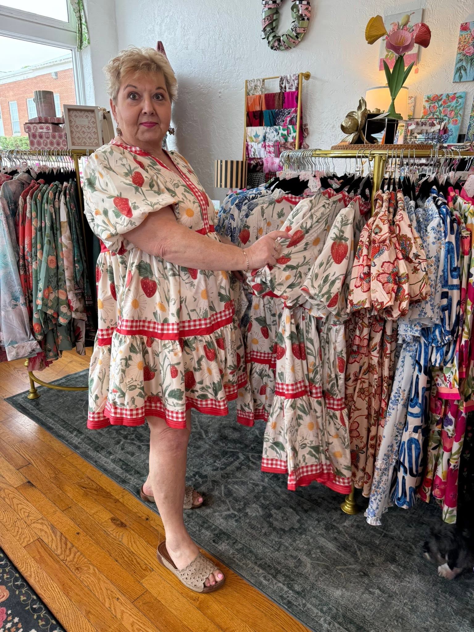 Woman in floral dress browsing colorful clothing racks inside a boutique.