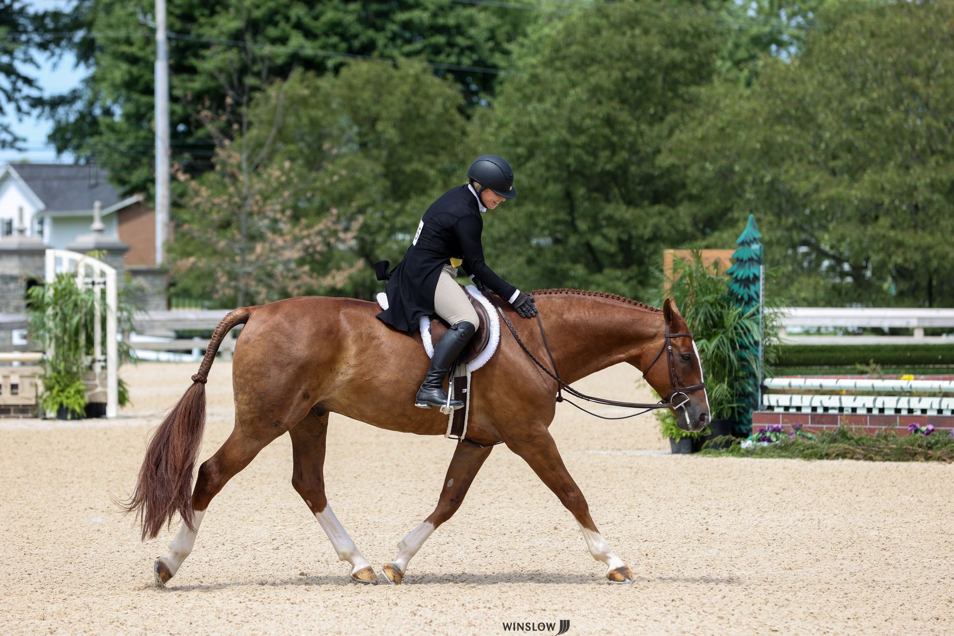 A man is riding a brown horse in a dirt arena.