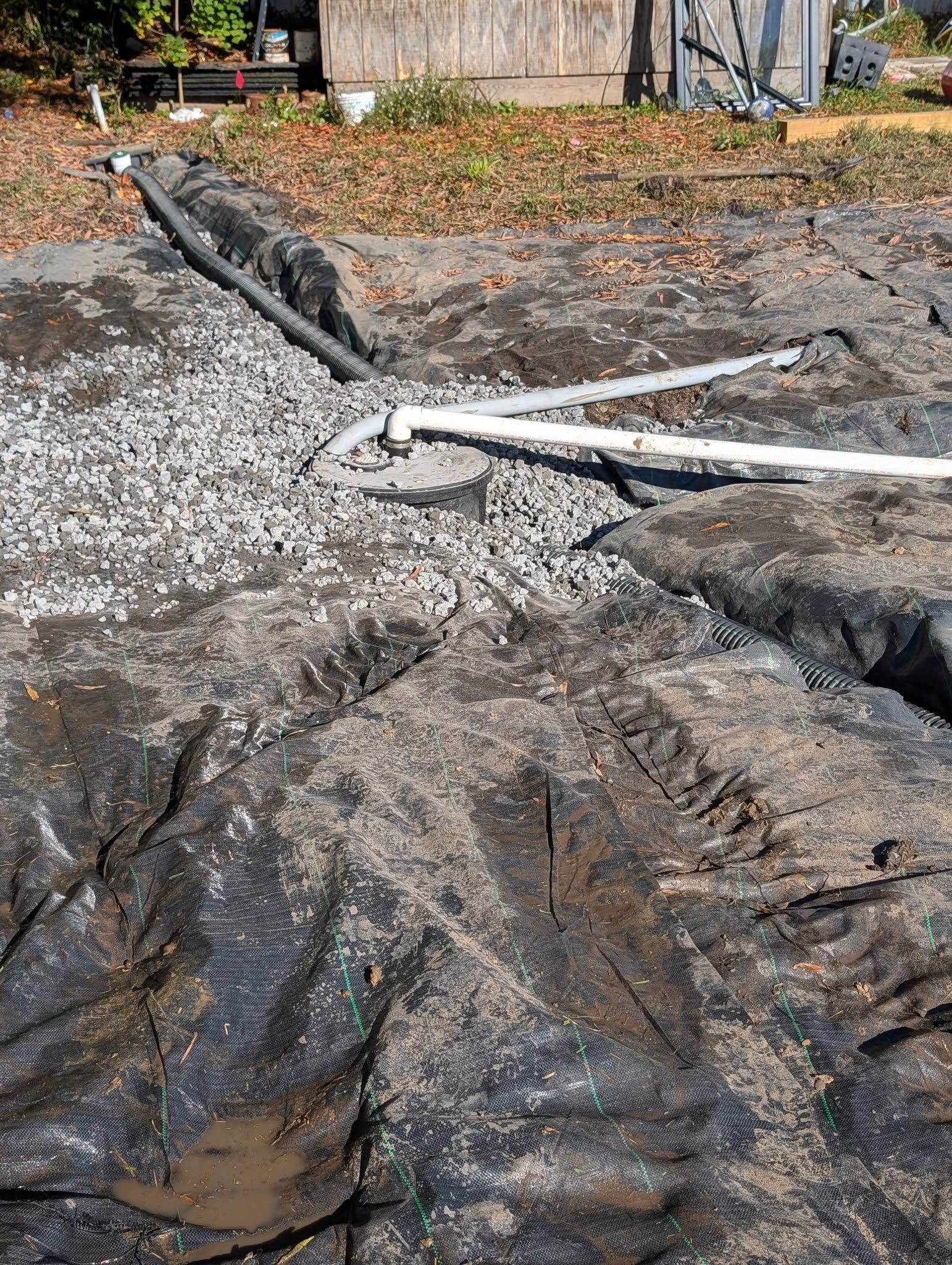 Collapsed pavement with exposed dirt and broken white pipes along a damaged roadside.