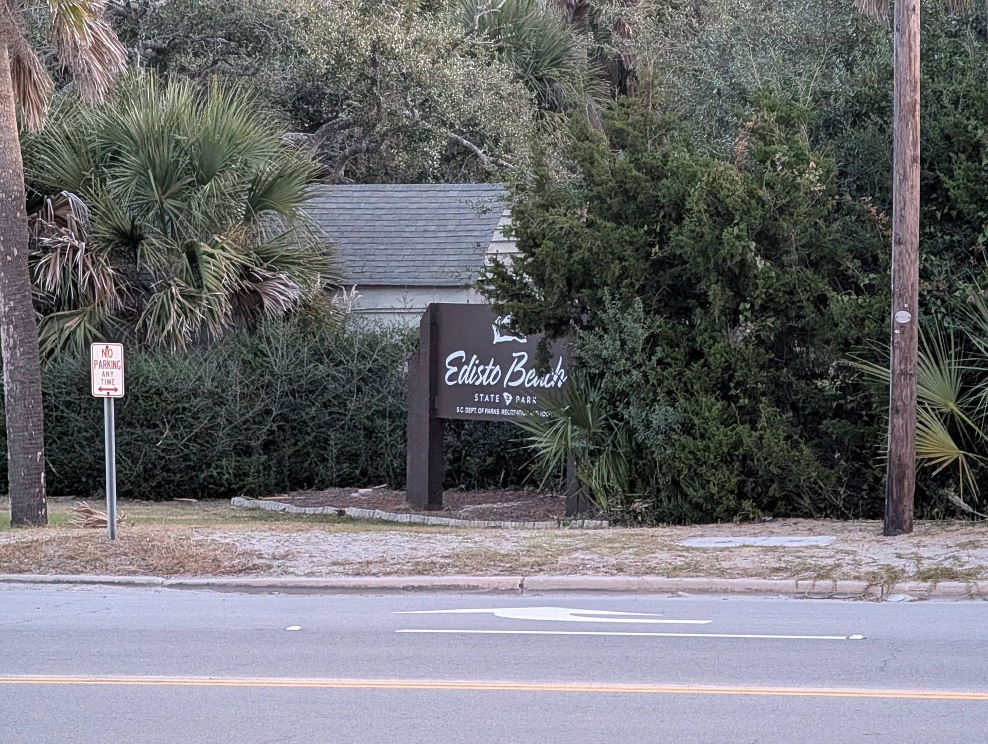 Roadside sign for Sun Valley amid dense greenery, beside a street and utility pole.