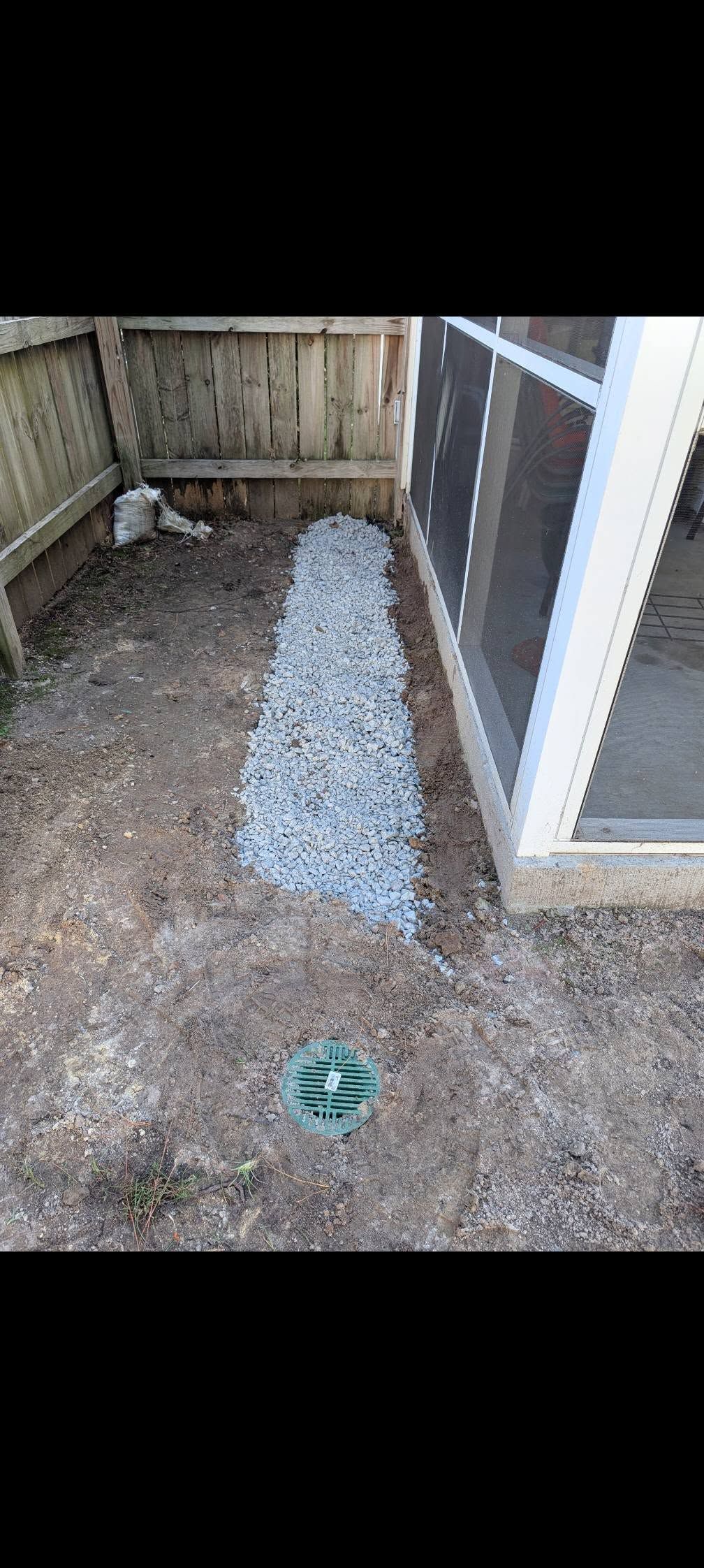 Small fenced yard with gravel path, wooden fence, and a screened door on the right.